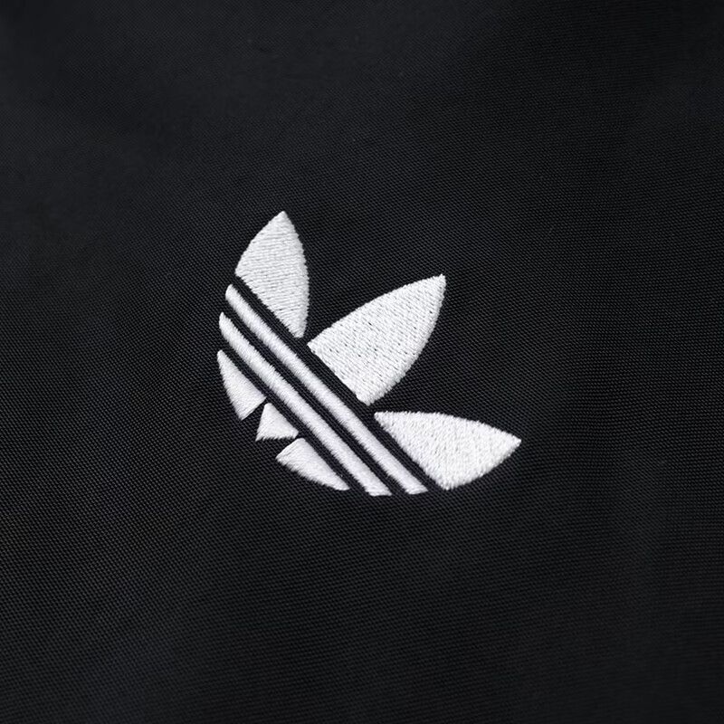 לוגו Trefoil רקום על ז׳קט adidas שחור, תקריב