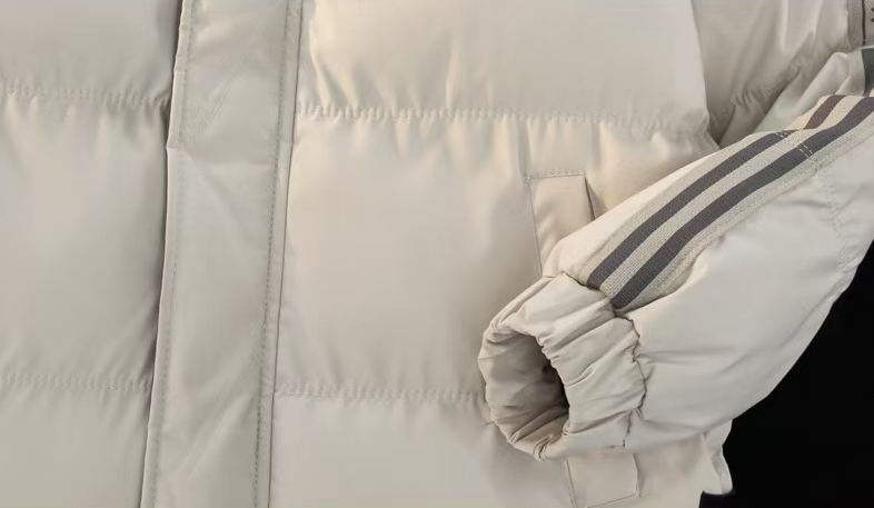 מעיל פוך adidas – תקריב שרוול עם פסי טייפ וקצה אלסטי